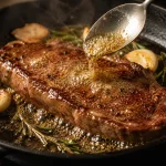 Steak tipis dibasting mentega dan bawang putih di wajan cast iron