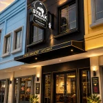 anskap jalan komersial modern di Gading Serpong saat sore hari dengan restoran dan lampu hangat.